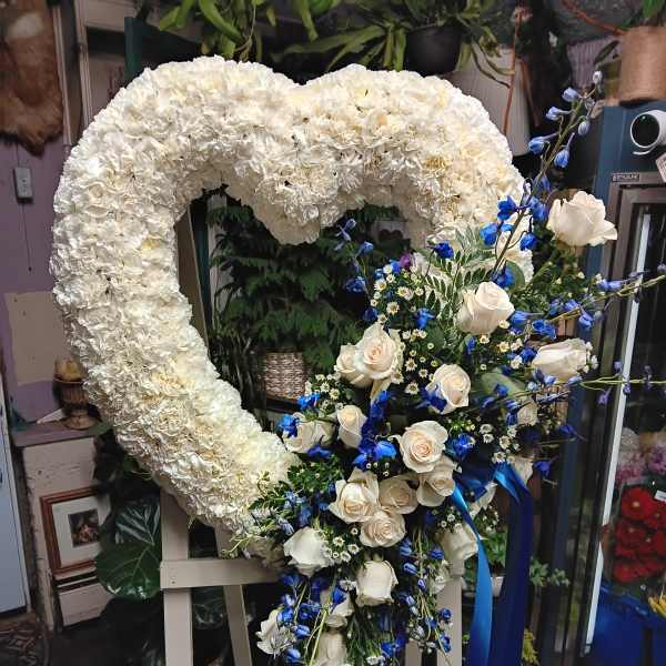 Heart-shaped white floral wreath with white roses and blue accents