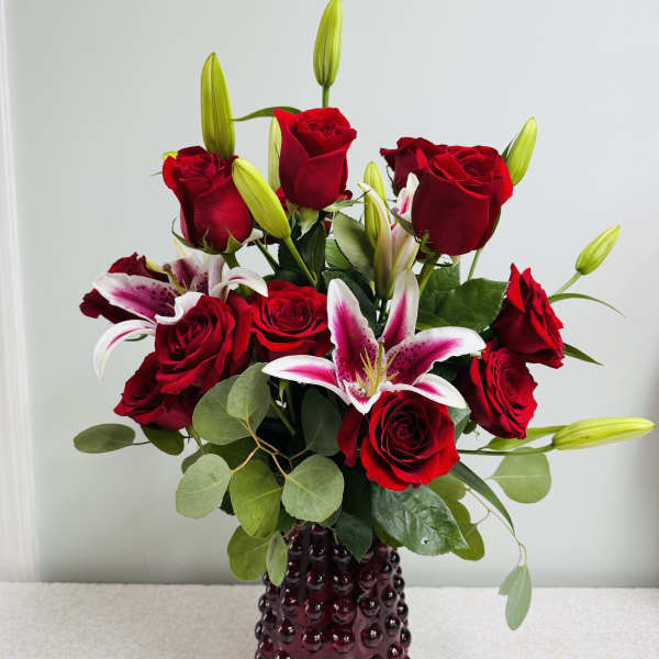 Red roses and pink lilies in a dark glass vase