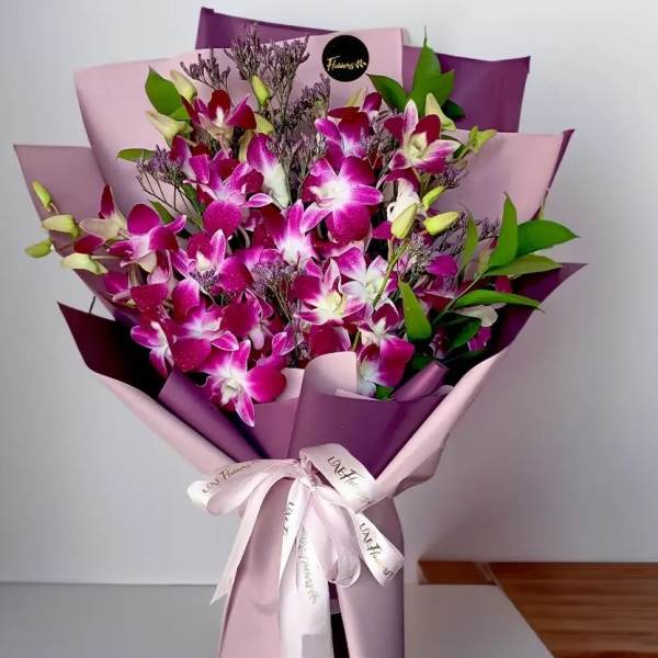 Bouquet of pink and white orchids wrapped in purple paper