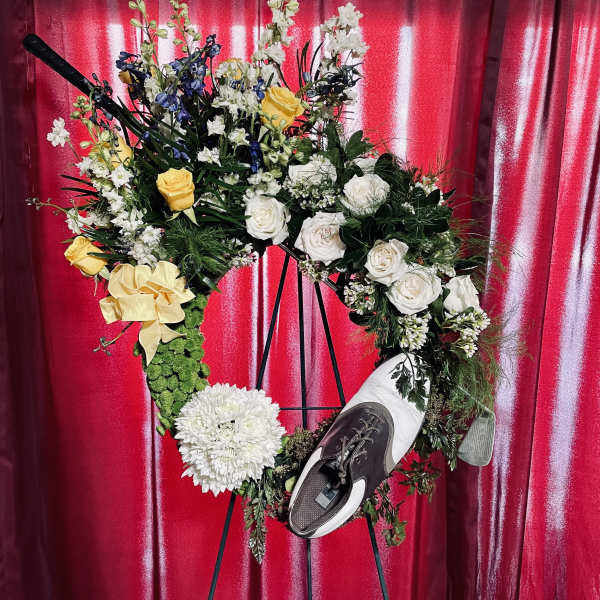 Floral wreath on an easel with white and yellow flowers and a shoe
