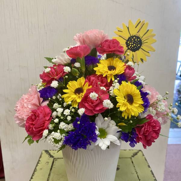 Colorful mixed bouquet in a white vase with daisies and carnations