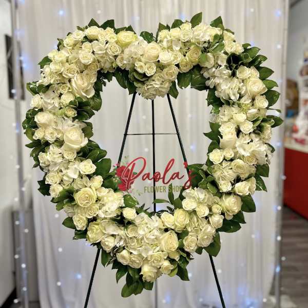 Heart-shaped white rose and hydrangea wreath on a stand