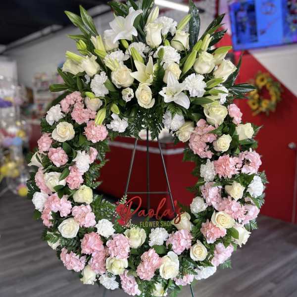 Large floral wreath with white lilies, roses, and pink carnations