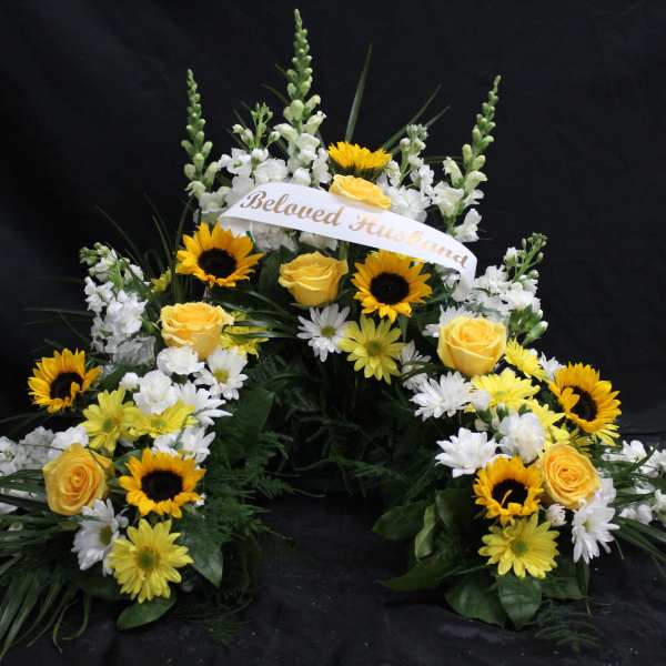 Sympathy floral spray with yellow roses, sunflowers, and white flowers