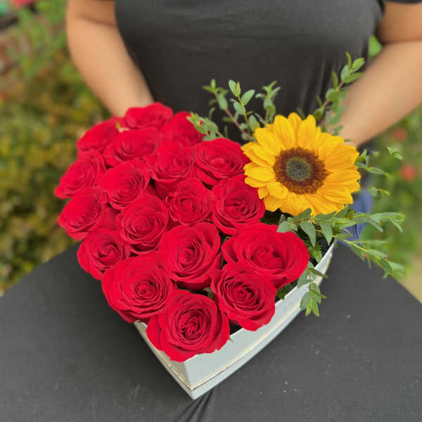 Heart-shaped box of red roses with a yellow sunflower