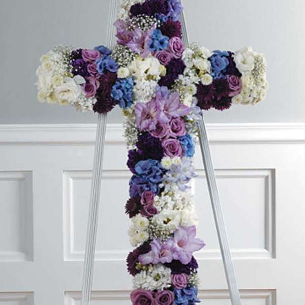 Floral cross arrangement on a standing easel with purple, blue, and white blooms