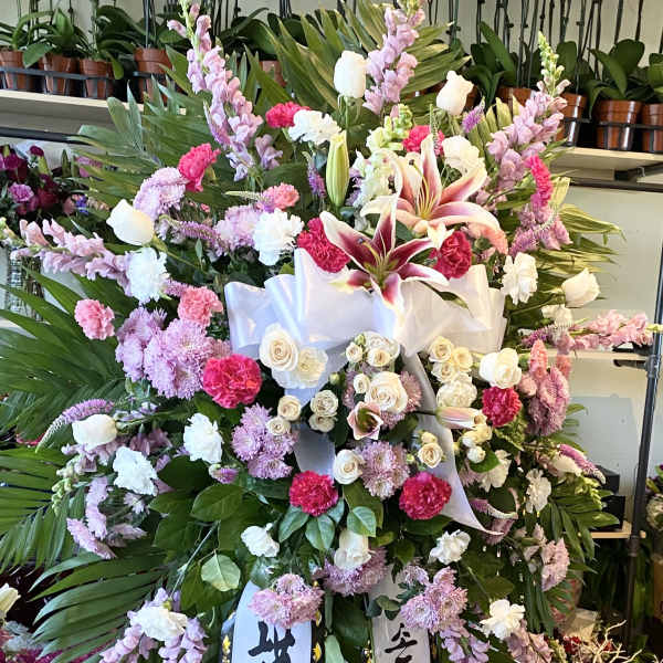 Large standing floral spray with pink, white, and purple flowers and ribbon streamers