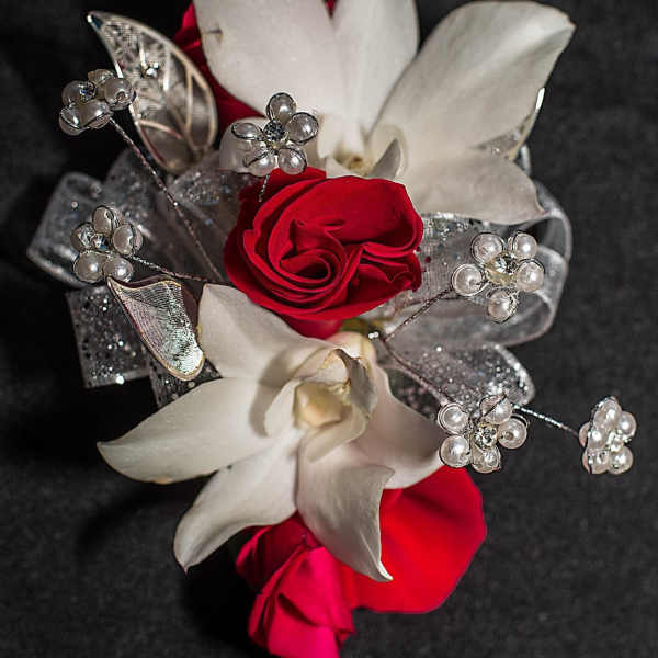 Red roses and white orchids with silver decorative accents on black fabric