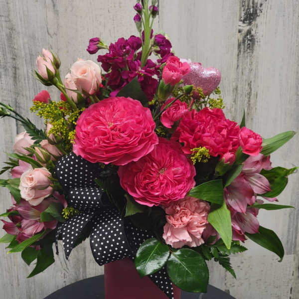 Pink and magenta bouquet in a tall vase with a polka-dot ribbon