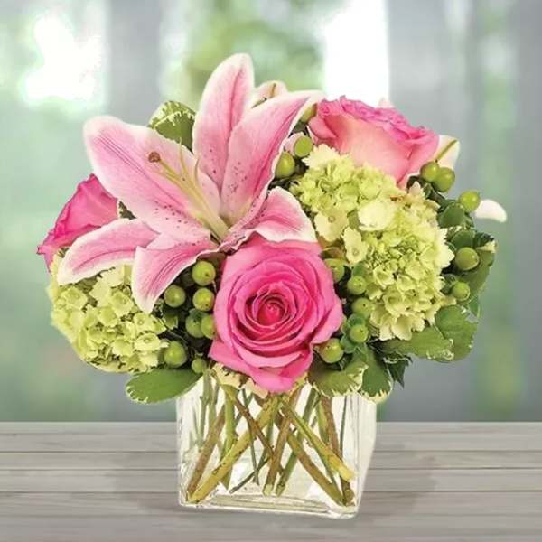Pink lilies and roses in a clear square vase
