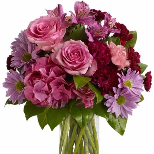 Pink roses and purple daisies in a clear glass vase