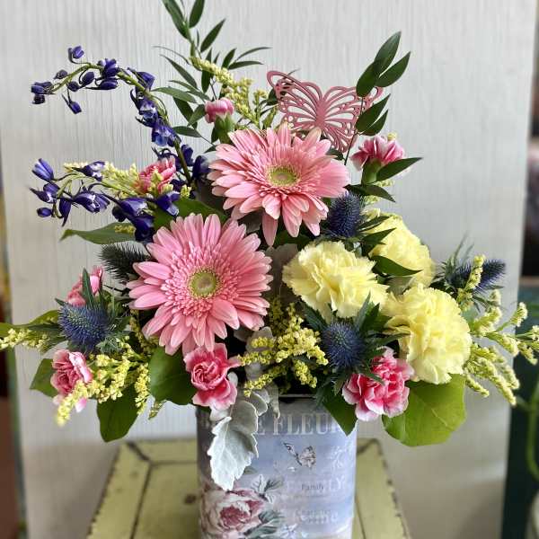Mixed bouquet in a decorative tin container with pink and yellow flowers