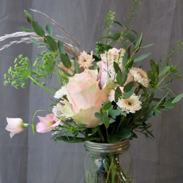 Pink roses and white daisies arranged in a glass jar vase