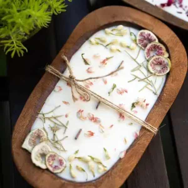 Oval wooden tray holding a white floral-scented candle with dried flower slices