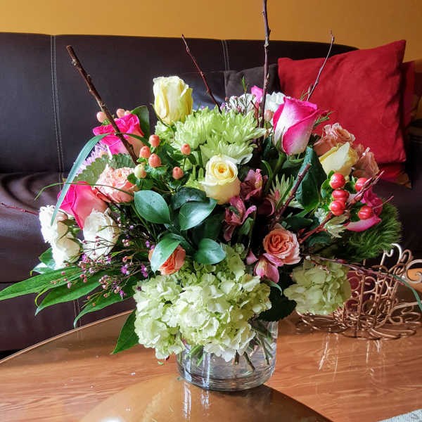 Mixed bouquet of roses, hydrangeas, and chrysanthemums in a glass vase