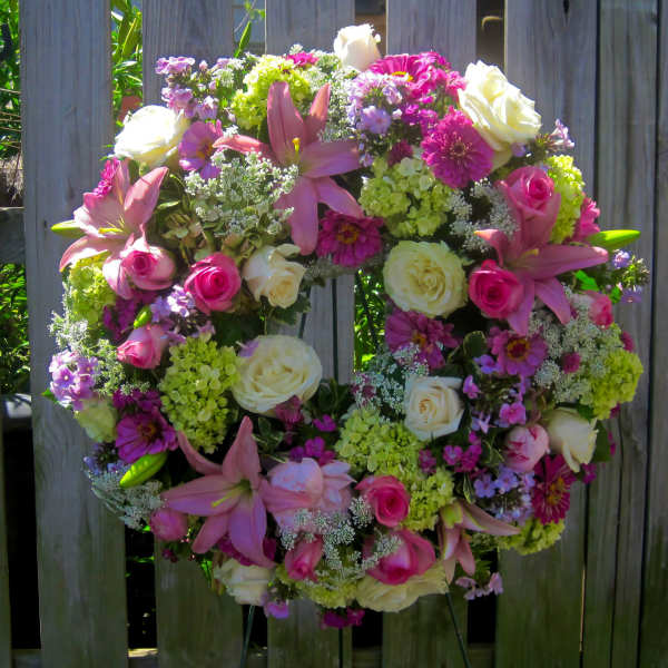 Heart-shaped floral wreath with pink lilies, roses, and green hydrangeas