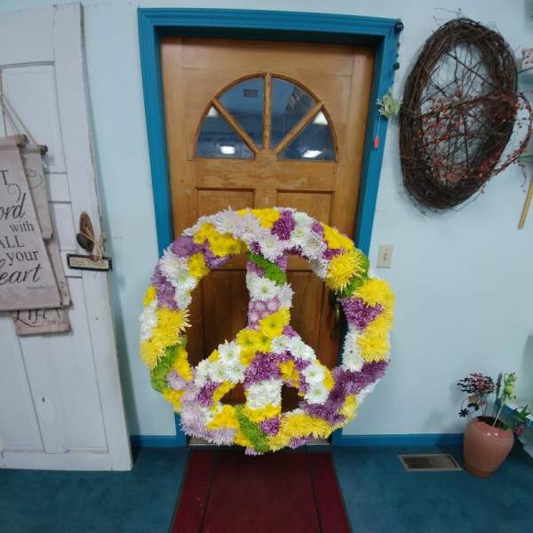 Large floral peace sign made of yellow, white, and purple flowers