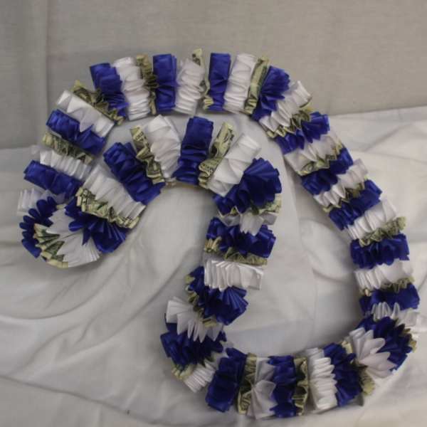 Blue, white, and money lei garlands arranged on a bed