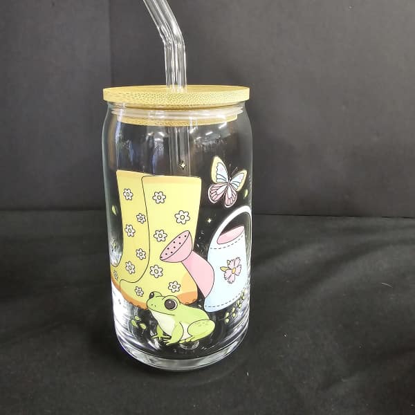 Clear glass tumbler with a bamboo lid and straw, decorated with a frog and butterfly graphic