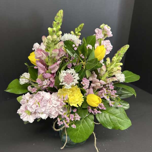 Mixed bouquet of pink and yellow flowers in a small vase