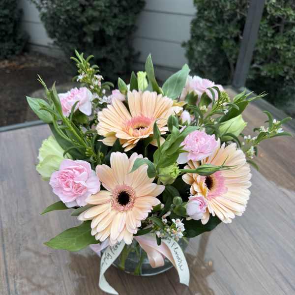 Bouquet of peach gerbera daisies and pink carnations in a glass vase