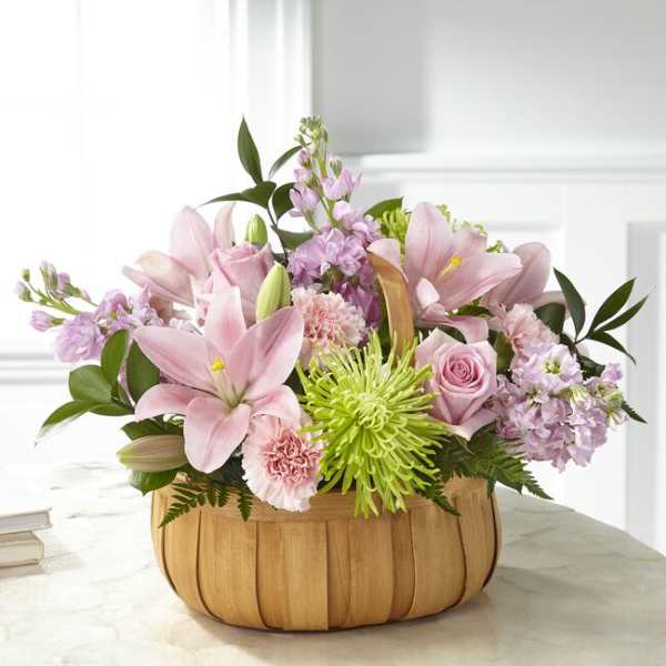 Pink lilies and roses in a wooden basket with green accents
