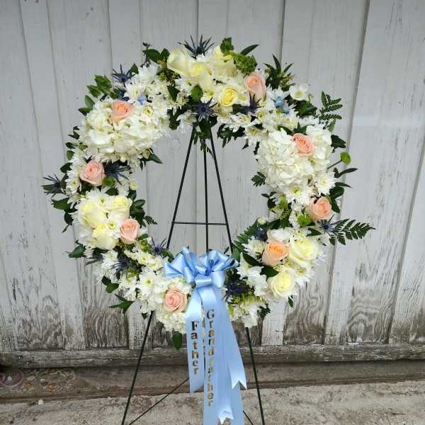 Heart-shaped floral wreath with white and peach flowers on a stand