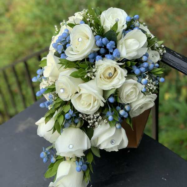 White rose bouquet with blue berries and greenery