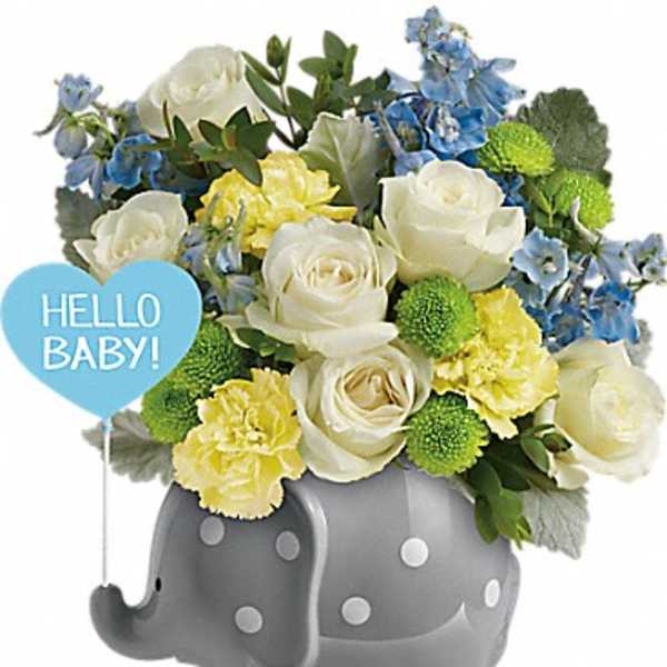 Bouquet of white roses, yellow carnations, and blue flowers in a gray elephant planter with a "Hello Baby" sign.