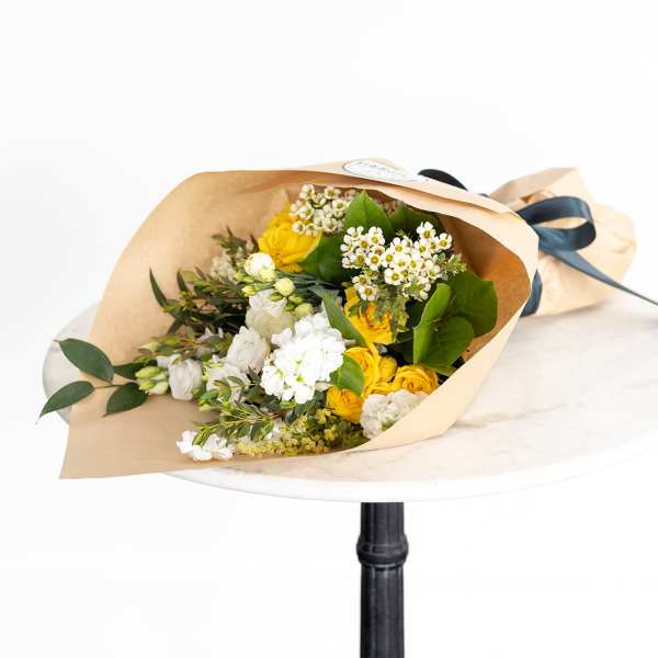 Bouquet of yellow and white flowers wrapped in kraft paper