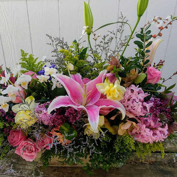 Large mixed floral arrangement with pink lilies and roses in a low container