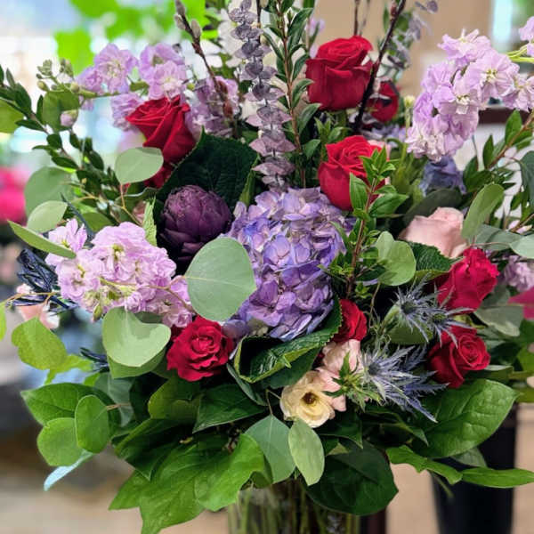 Bouquet of red roses and lavender flowers in a glass vase