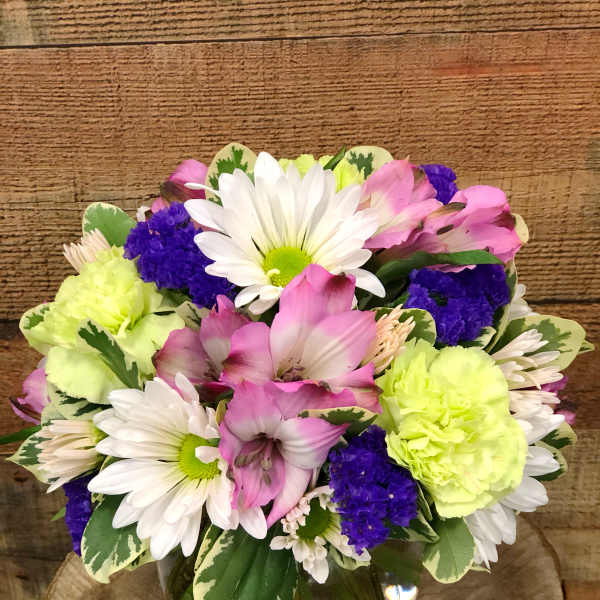 Mixed bouquet of daisies, pink alstroemeria, and carnations in a glass vase