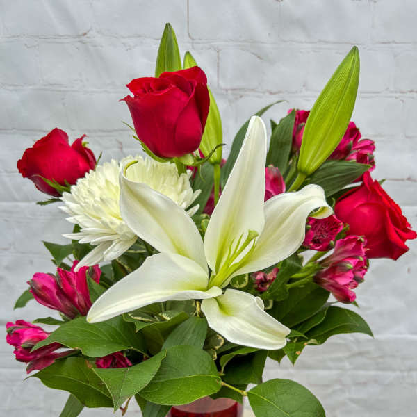 Red roses and white lilies in a red glass vase