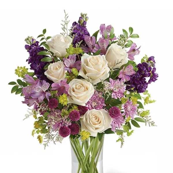 Bouquet of white roses and purple flowers in a clear glass vase