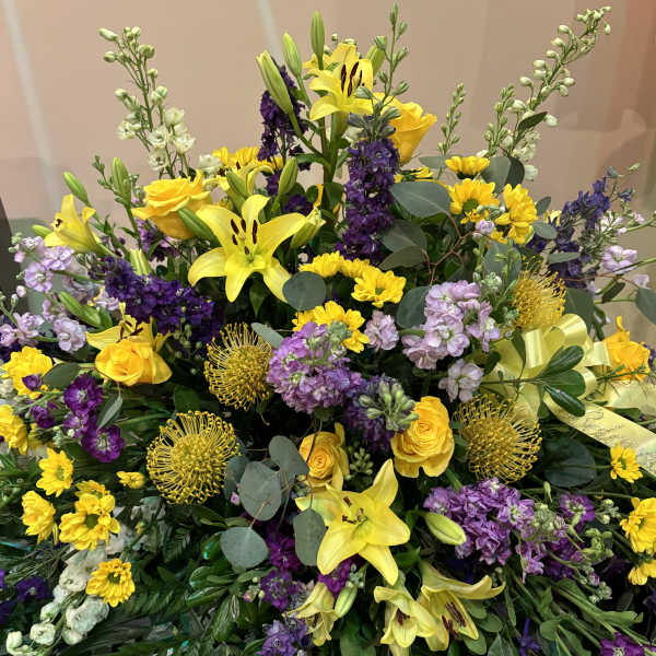 Large bouquet of yellow lilies, purple flowers, and yellow roses