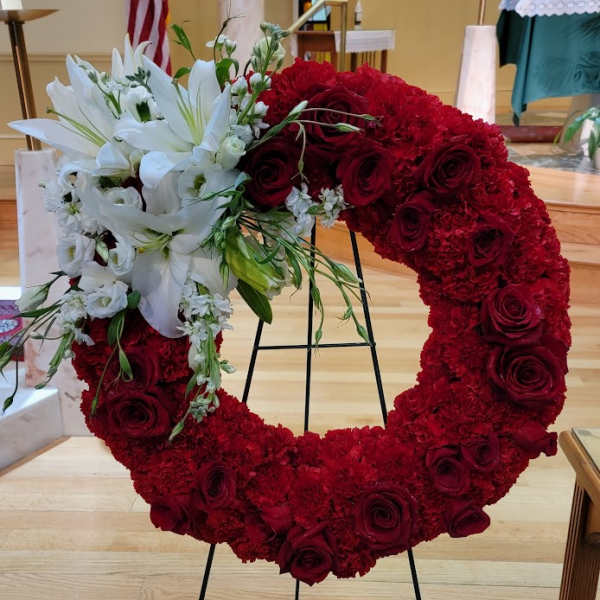 Heart-shaped red floral wreath with white lilies and roses