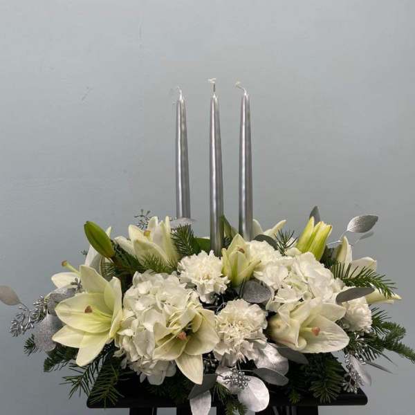 White lilies and hydrangeas arranged with three silver candles