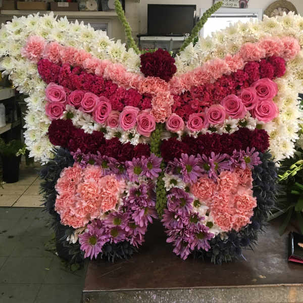 Large butterfly-shaped floral arrangement with pink, white, and purple flowers