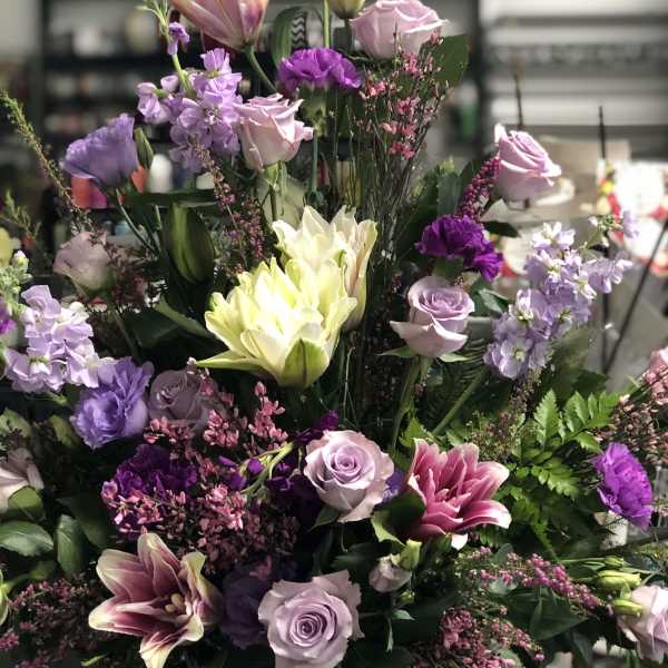 Tall mixed bouquet of pink, purple, and white flowers in a black vase