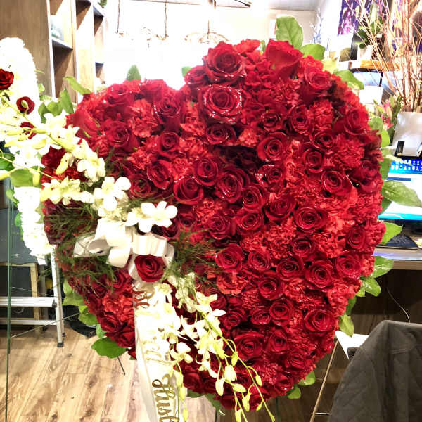Large heart-shaped red rose arrangement with white orchids and ribbon