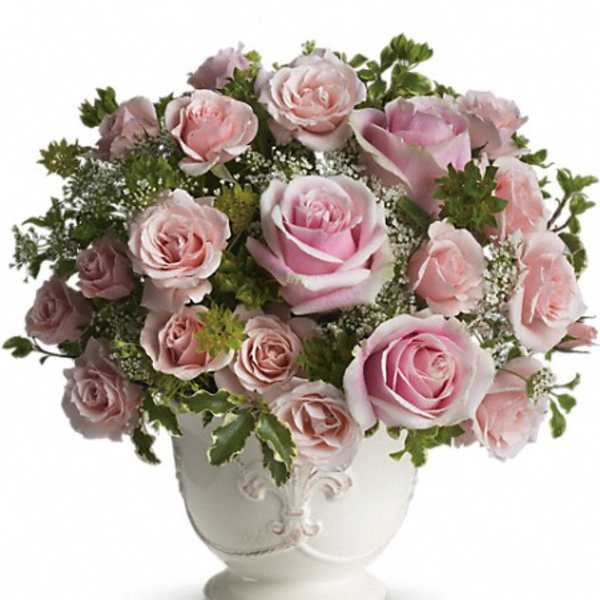 Pink roses arranged in a white urn vase