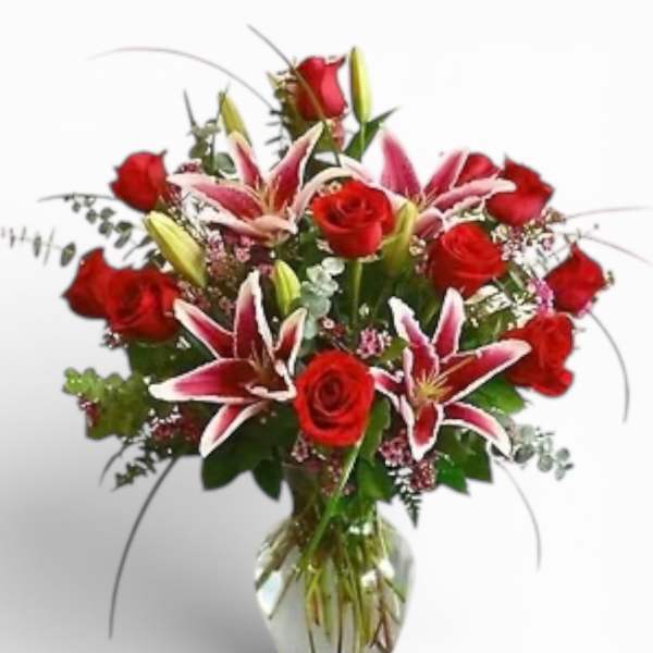 Red roses and pink lilies arranged in a clear glass vase