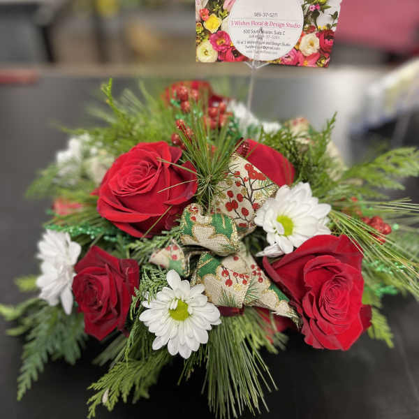 Red roses and white daisies in a low holiday bouquet with pine accents