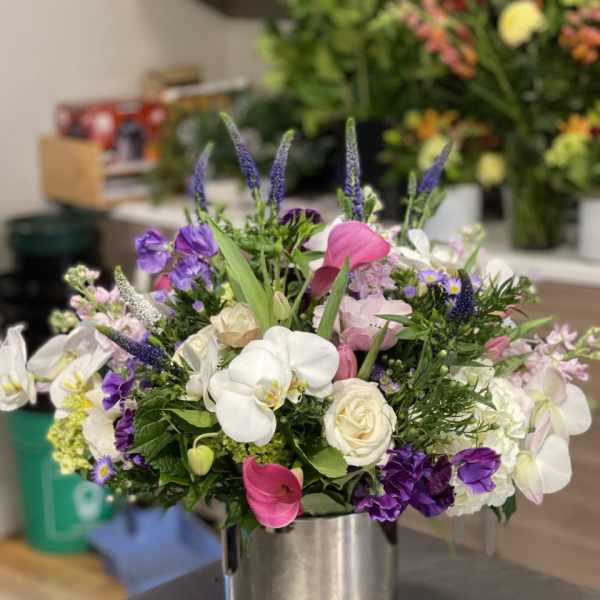 Mixed bouquet of white, pink, and purple flowers in a silver vase