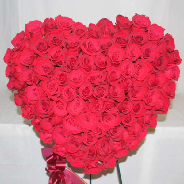 Heart-shaped bouquet of red roses with a ribbon at the base