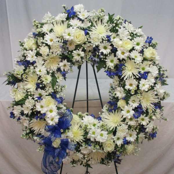 Large white and blue floral wreath on a black stand