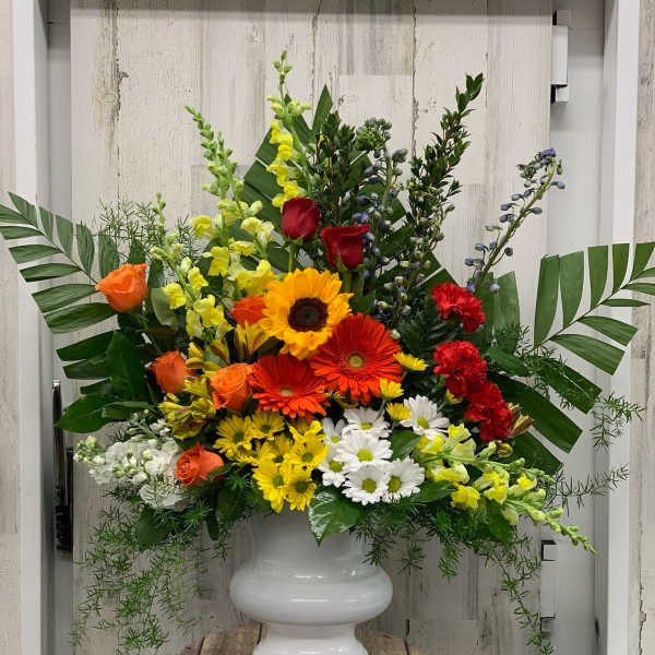Large mixed flower arrangement in a white urn vase