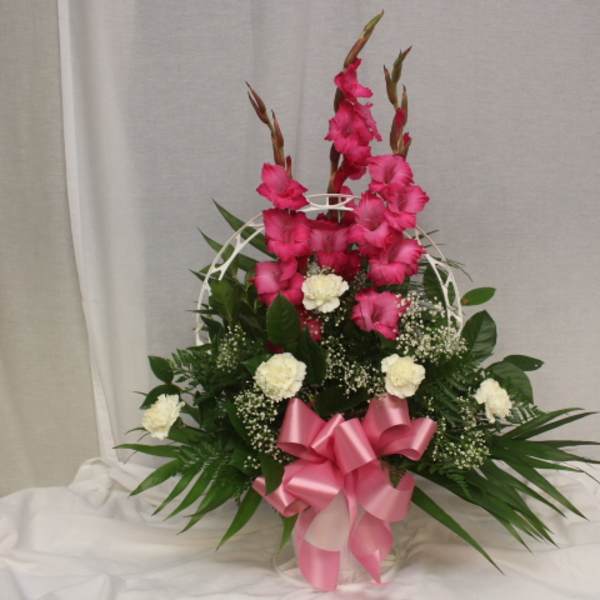 Pink gladiolus arrangement with white carnations in a basket and pink ribbon