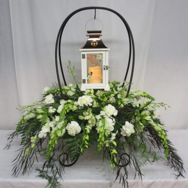 White floral funeral lantern arrangement with a framed lantern centerpiece